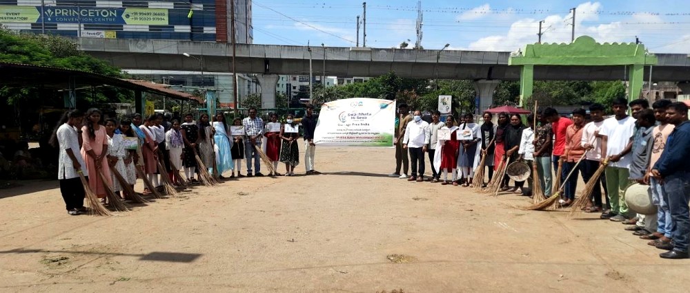 Volunteers lined up with brooms for a community clean-up